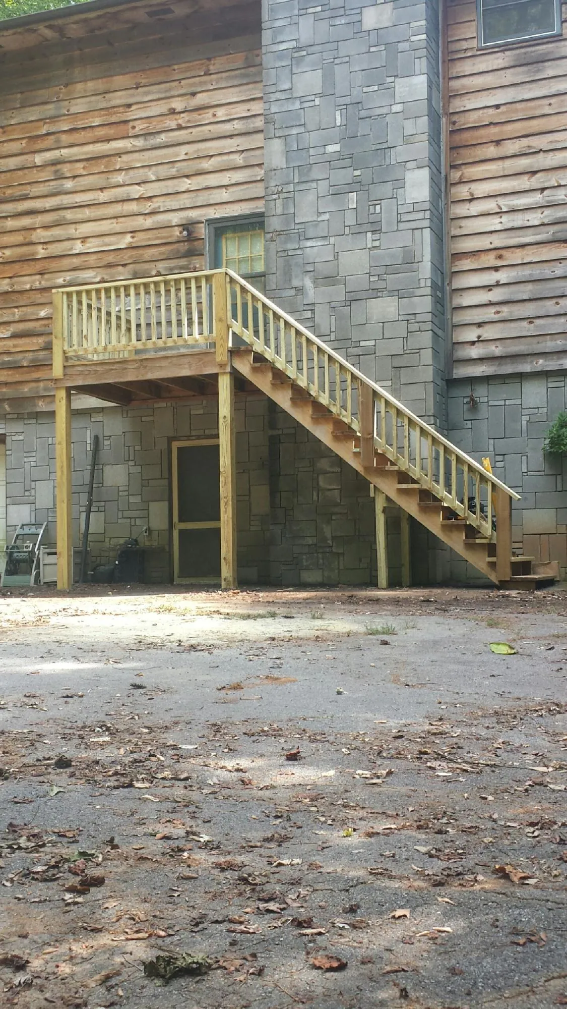 New pressure treated deck and stair landing on a log home in Essex