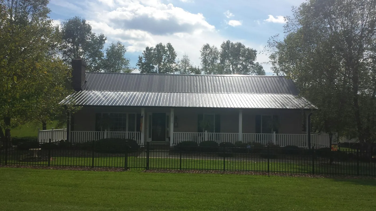 Gray metal roof on a brick ranch with a full width front porch — Gutter Guard Installation work by our crew in Essex